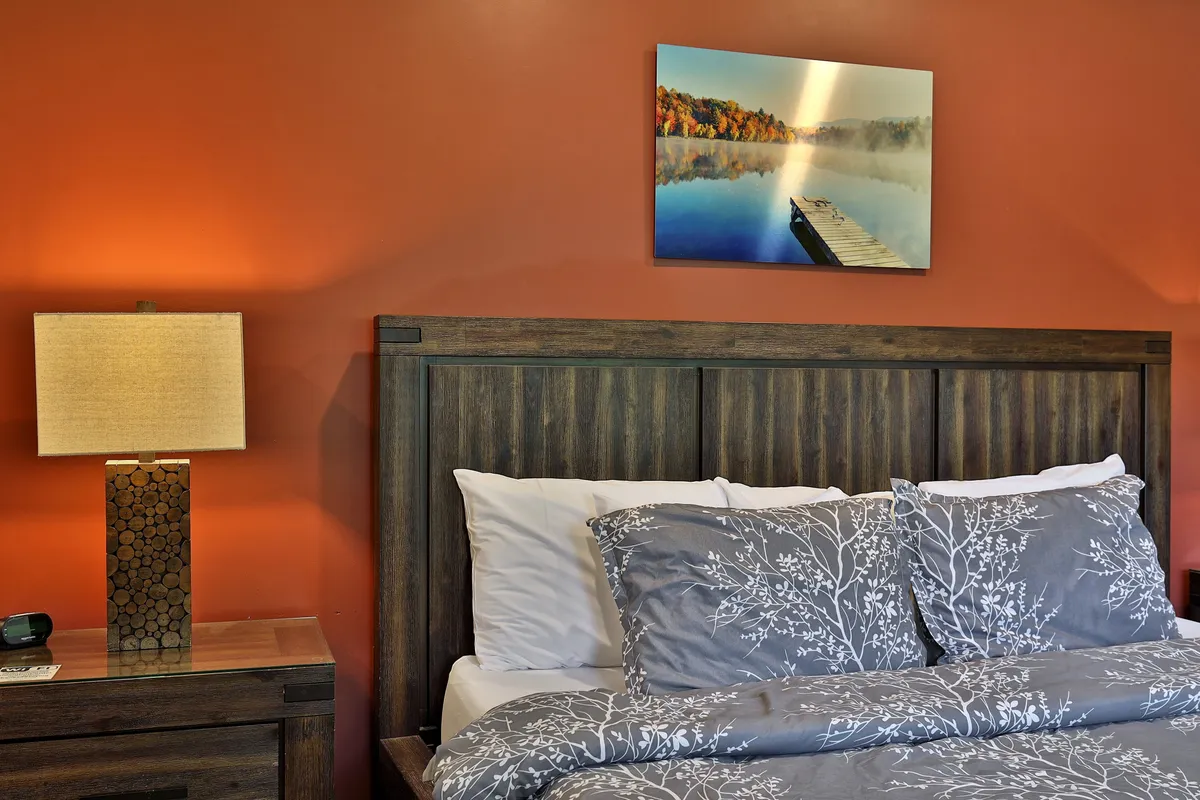 A tranquil bedroom scene with patterned bedding, a bedside lamp for reading, and calming artwork above the bed. The soft lighting and serene decor create an atmosphere ideal for restful sleep and relaxation, emphasizing guest comfort.