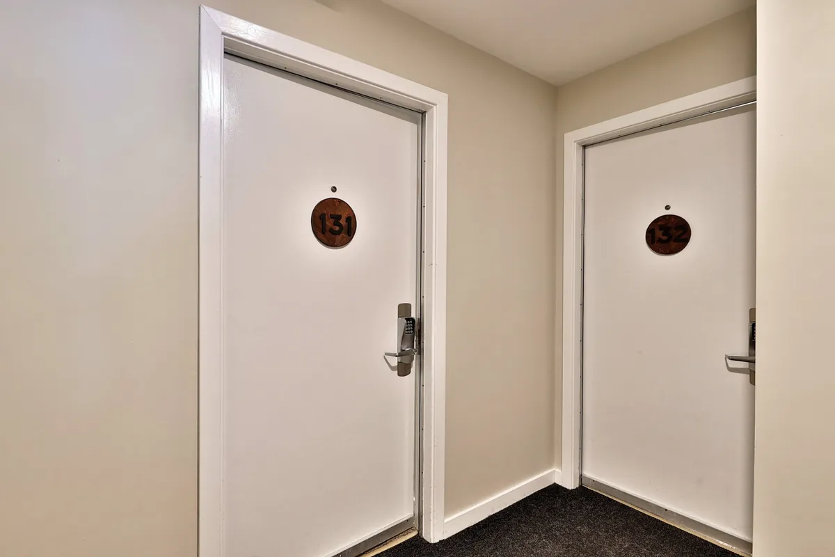 This image highlights a private, modern hallway with two numbered doors, hinting at the condo-style privacy and exclusivity of the accommodations. The mood is inviting yet private, underscoring the sense of personal space.