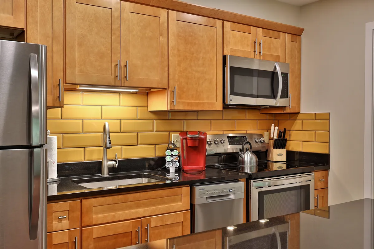 A bright, modern kitchen with stainless steel appliances, a distinctive yellow backsplash, and black countertops, creating a warm and welcoming space ideal for cooking and socializing after outdoor adventures.