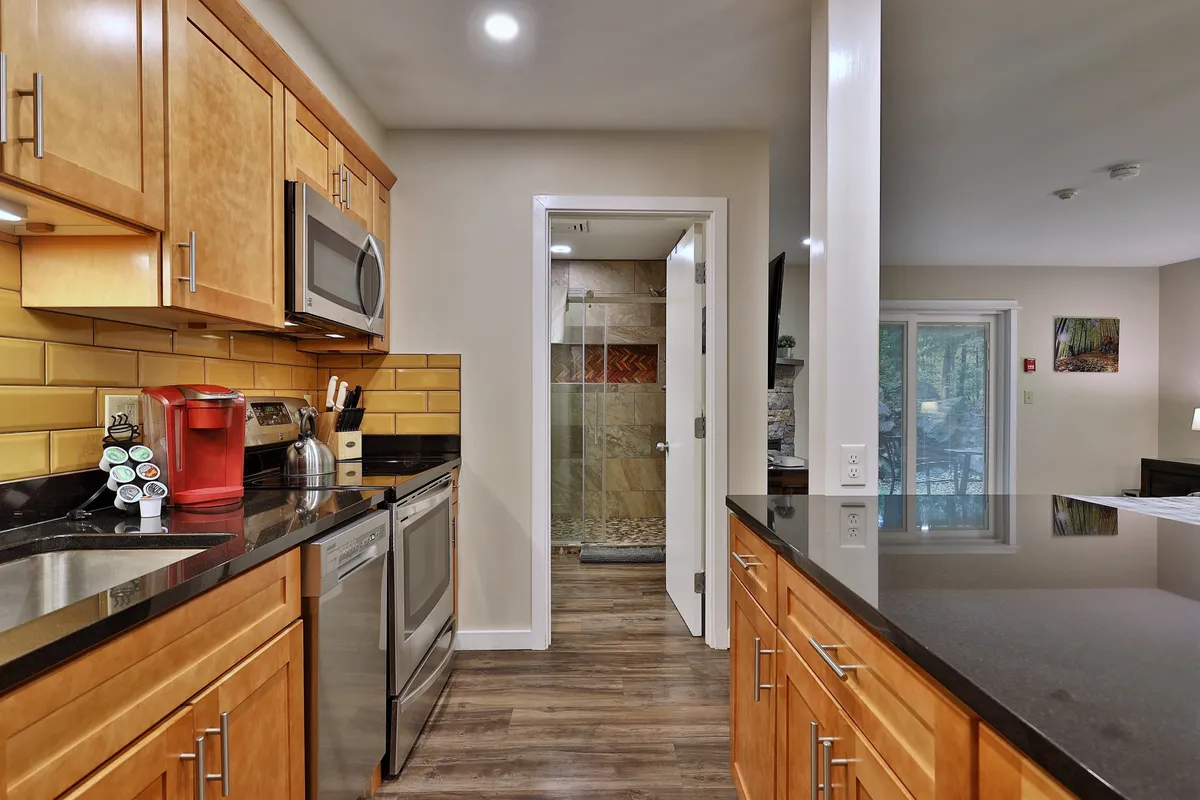 A cozy, contemporary kitchen featuring sleek countertops, stainless steel appliances, and a view into a bathroom, highlighting the suite's modern touches and open layout for family gatherings or entertaining.
